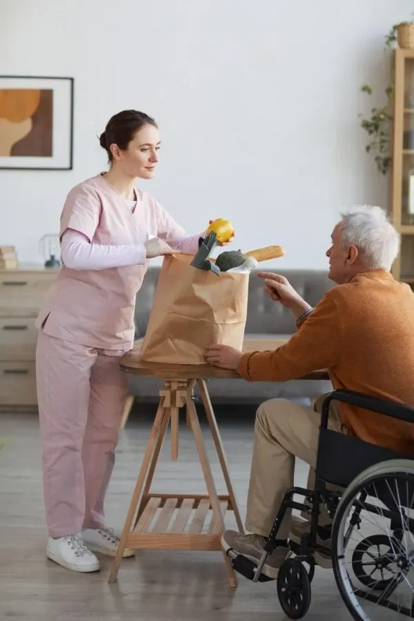 vertical-full-length-portrait-young-female-caregiver-bringing-groceries-senior-man-wheelchair-assistance-food-delivery-concept-r4jmn0apdqggg3fdo3wn8nxny70a6wix3uzkyd3g2w